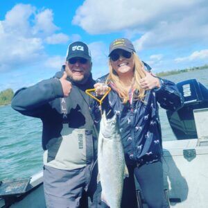 Happy woman with her spring salmon she caught on the Columbia River, with Portland Oregon fishing guide Marvin Henkel.